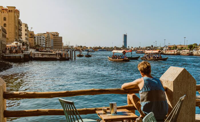Tourist enjoying Dubai Creek waterfront views and traditional boats in Dubai
