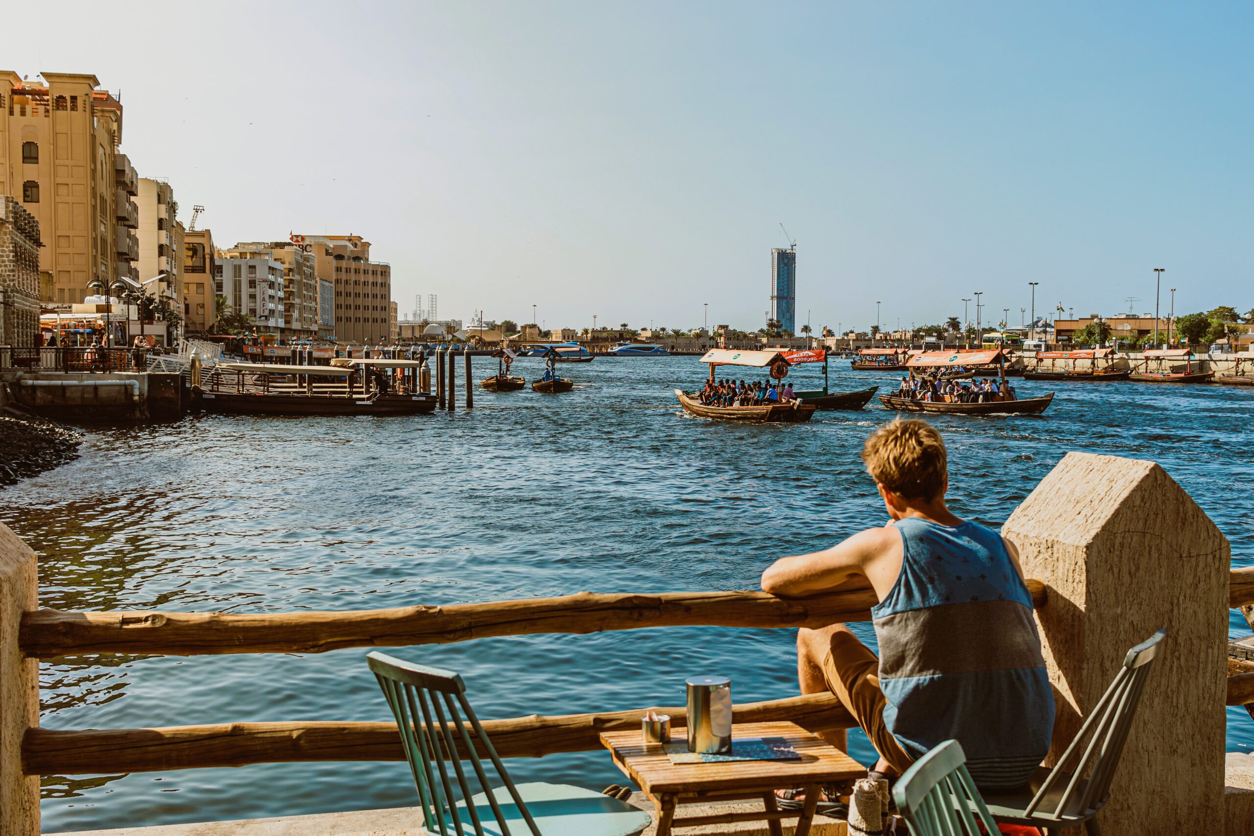 Tourist enjoying Dubai Creek waterfront views and traditional boats in Dubai