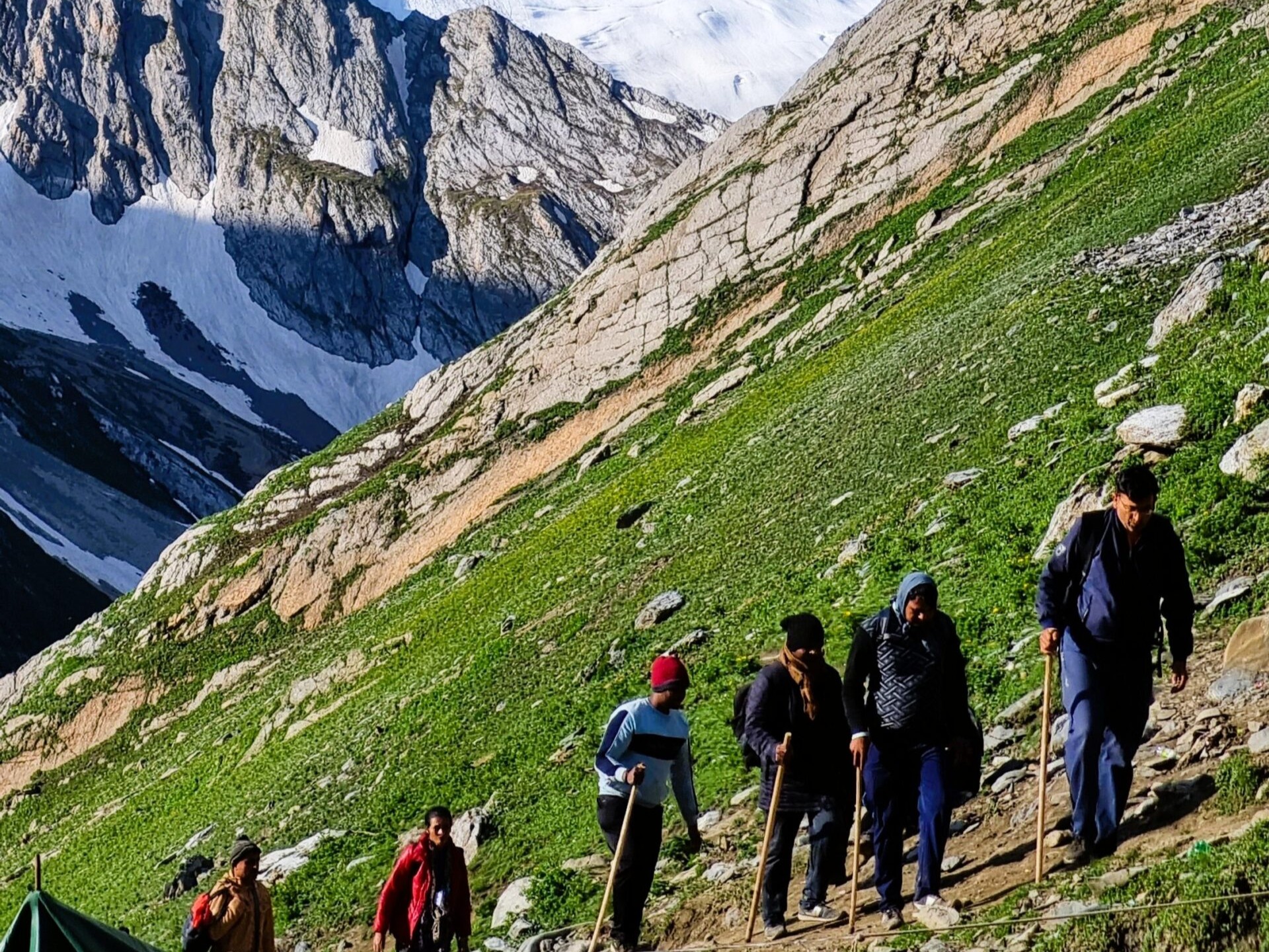 Pilgrims trekking along the Amarnath Yatra route with snow-covered Himalayan peaks in Kashmir India Getaways